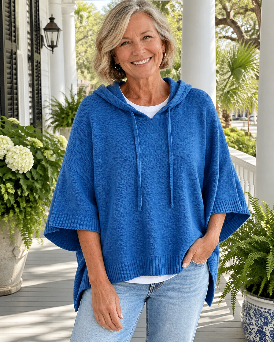 Woman wearing the blue hooded knit poncho sweater on a Charleston porch